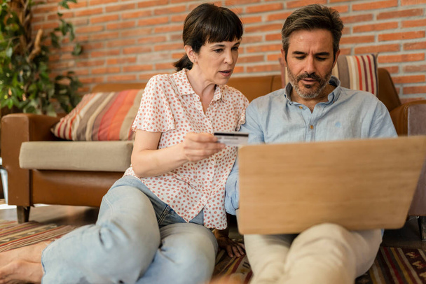 Happy senior husband, wife, mature couple, family, Caucasian mature, adult and retiree using laptop with credit card, shopping online at home, paying for groceries, paying by browsing internet. - 写真・画像
