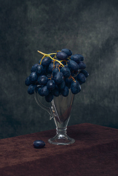 Still life with a branch of grapes on a glass - Фото, зображення