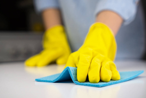 Woman in yellow rubber gloves wipes the dust on the table with a rag. Housekeeping concept. Close-up. Selective focus. - Foto, immagini