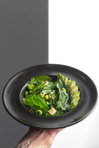 Healthy food. Fresh green salad on a black plate. Healthy vegetarian lunch. Restaurant vegan food. - 写真・画像