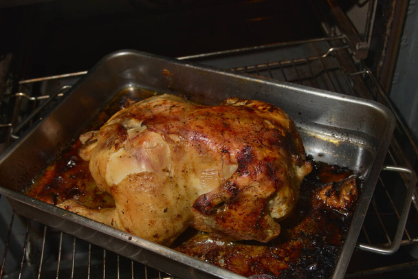 Primer plano de un pollo recién asado mientras está en la bandeja dentro del horno - Foto, Imagen