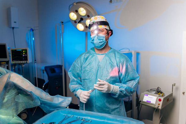 Portrét profesionálního mužského chirurga proktologa před operací držícího anoskop na operačním sále v nemocnici. Naléhavý chirurgický koncept - Fotografie, Obrázek