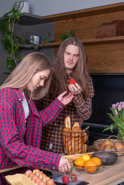 Mladý pár v kuchyni, Mladá žena sbírá jahody, dlouhé  - Fotografie, Obrázek