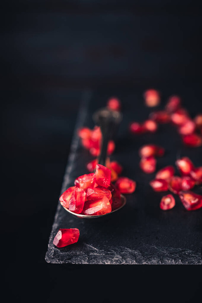 Pomegranate seeds on an old vintage spoon isolated on a slate stone table. space for text. vintage style - Foto, Bild