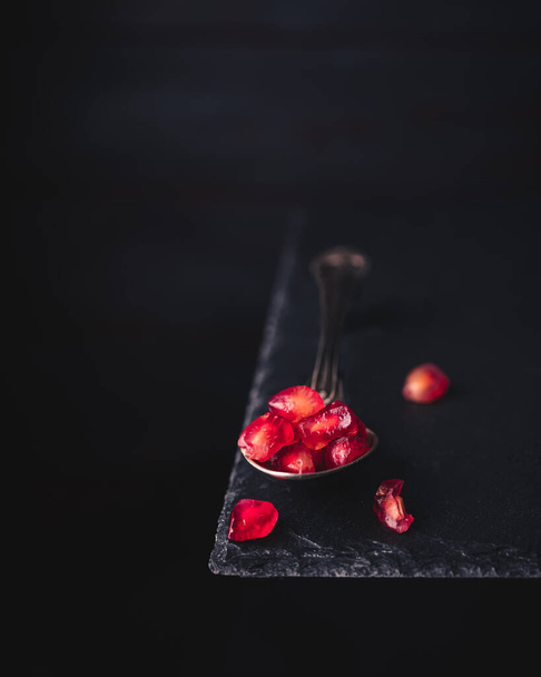 Pomegranate seeds on an old vintage spoon isolated on a slate stone table. space for text. vintage style - Foto, immagini