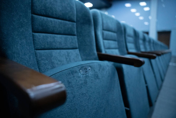 Пустые ряды сидений в зале для большого количества людей. Кинотеатр и зал для просмотра спектаклей и фильмов. - Фото, изображение