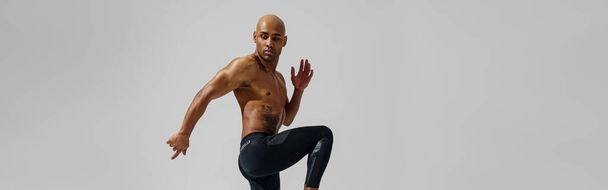 Active sporty man with naked torso jumping on white studio background. Dynamic movement - Zdjęcie, obraz
