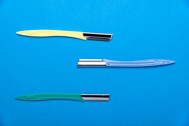 multi-colored women's razors with plastic handles on a blue background. Space for text. - Photo, Image