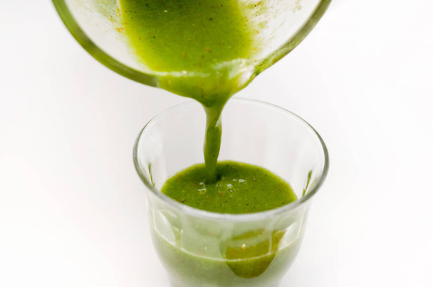 Налейте здоровый зеленый смузи в стекло. Зеленый смузи из зеленых листовых овощей и фруктов - Фото, изображение