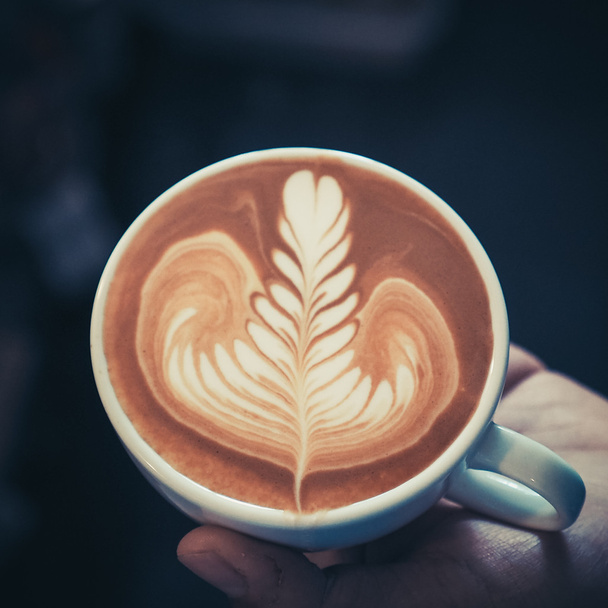 ヴィンテージ色の木製の背景にコーヒー カフェラテ アートのカップ  - 写真・画像