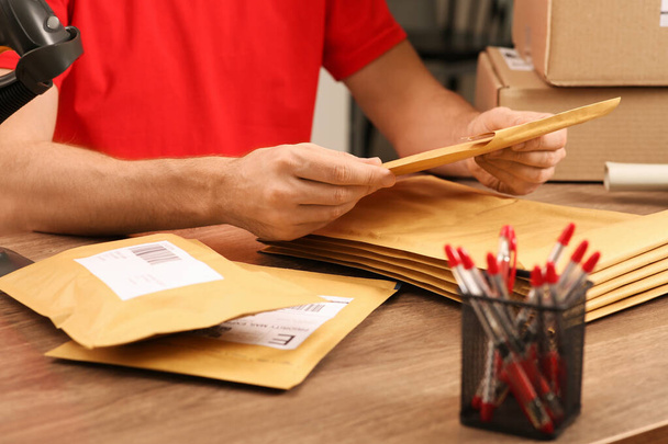 Post office worker with adhesive paper bags at counter indoors, closeup - Photo, image