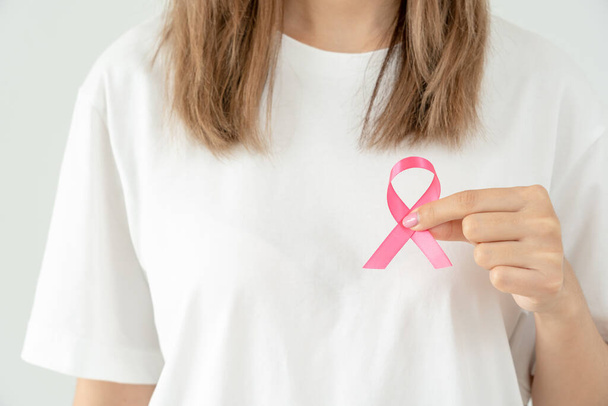 Woman hold pink ribbon breast cancer awareness. Female health check consciousness. international Women Day and World Cancer Day. sign cancer, Symbolic, health care, support patients, timely diagnosis - Fotografie, Obrázek