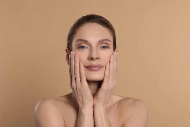 Woman massaging her face on beige background - Photo, Image