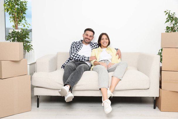 Happy couple resting on sofa in new apartment. Moving day - Foto, afbeelding