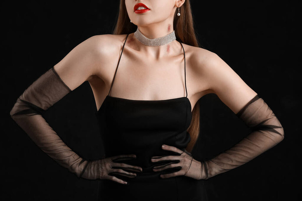 Beautiful woman in black dress with love bites on her neck against dark background - Photo, Image