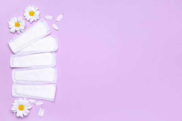 Složení s menstruačními polštářky a heřmánkovými květy na šeříkovém pozadí - Fotografie, Obrázek