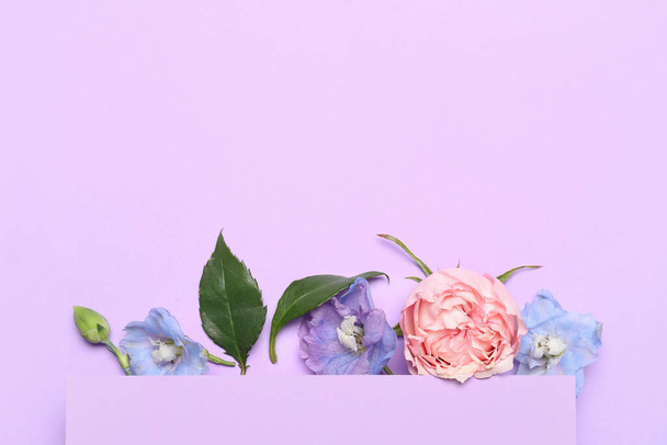 Hermosa composición con tarjeta y flores sobre fondo lila - Foto, Imagen