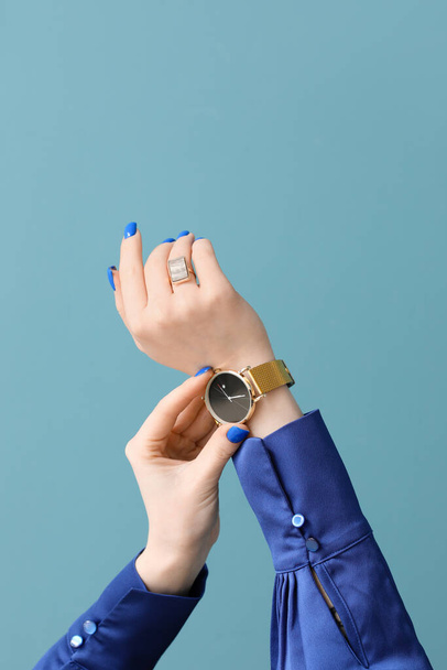 Woman with golden wristwatch on blue background - Фото, зображення