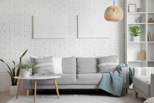 Sofás cinzentos com almofadas e planta de sala na mesa no interior da sala de estar - Foto, Imagem