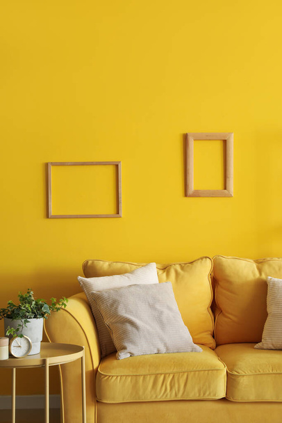 Interior de la sala de estar con sofá amarillo y marcos - Foto, imagen