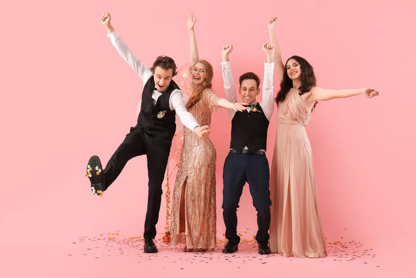 Beautiful couples dressed for prom on pink background - Photo, Image