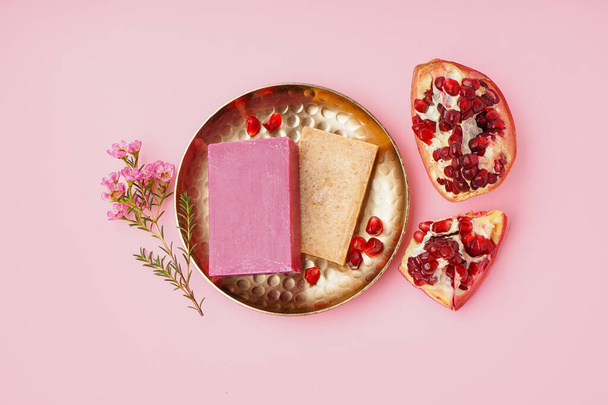 Plate with natural soap bars, flowers and pomegranate on pink background - Foto, immagini