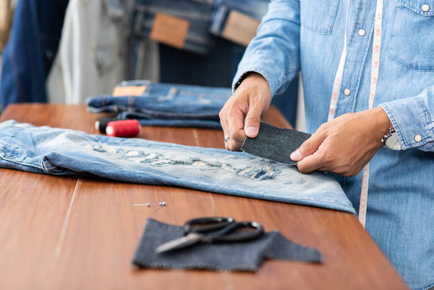 Krawiec pracujący w dżinsach. Naprawa jeansów jeansowych. - Zdjęcie, obraz