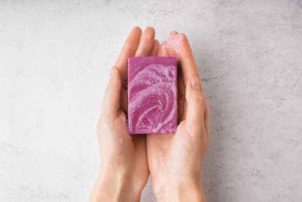 Female hands with natural soap bar on light background, closeup - 写真・画像