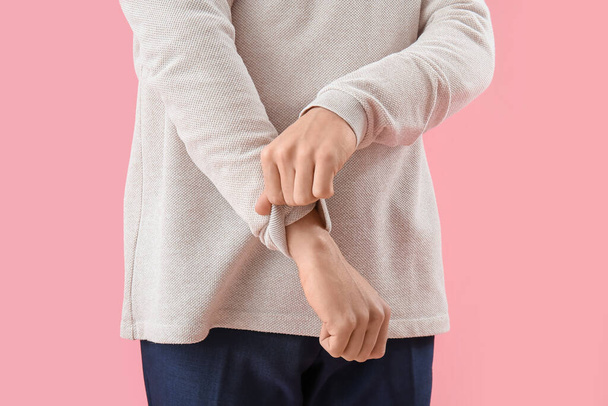 Young man rolling up his sleeve on pink background, closeup - Φωτογραφία, εικόνα