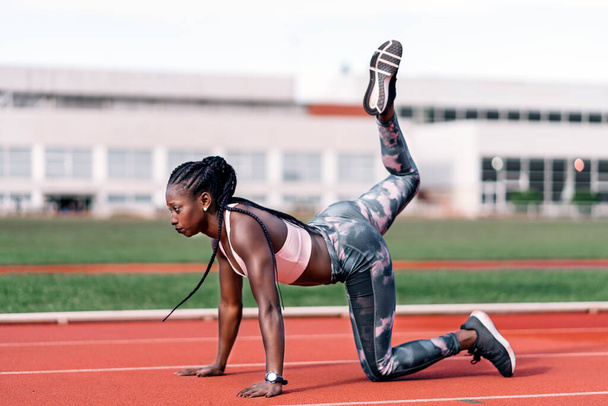 Stock photo of an African-American sprinter stretching her legs before training - Фото, зображення