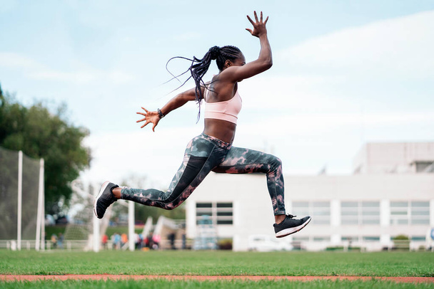 Stock photo of an African-American sprinter jumping in the sports center - Fotó, kép