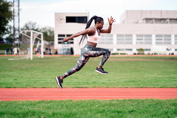 Stock photo of an African-American sprinter jumping in the sports center - Foto, Bild