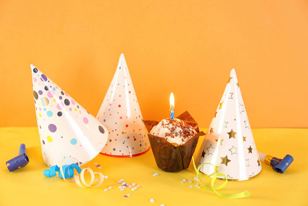 Verjaardag cupcake, party hoeden, fluitjes en confetti op kleur achtergrond - Foto, afbeelding