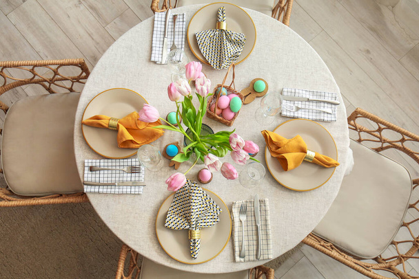 Table with tulip flowers and painted eggs served for Easter celebration - Photo, Image