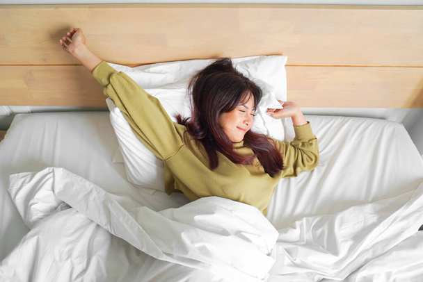 Portrait of beauty happy Asian woman awaking, wake up on the bed (sleep). Young beautiful Asian girl stretching her arms in fresh early morning, relax peaceful morning routine yawn concept banner - Φωτογραφία, εικόνα