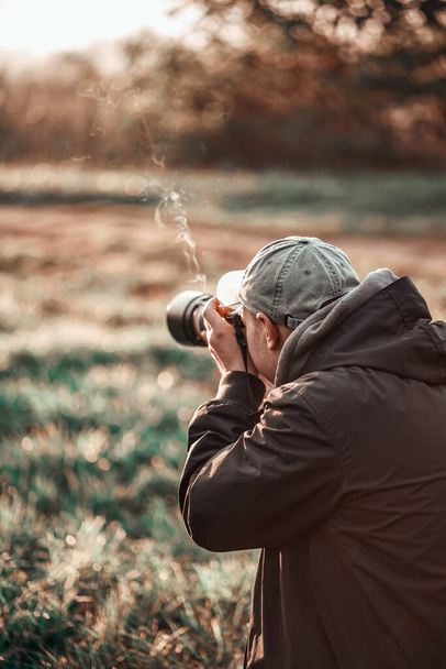 Hombre tomando fotos al aire libre. Fotógrafo profesional que toma fotografías de paisajes y vida silvestre. Cámara grande - Foto, imagen