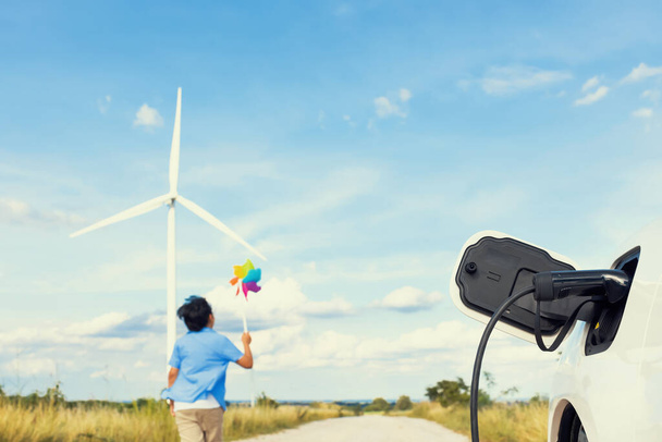 Прогресивний молодий азіатський хлопчик, який грає з іграшкою вітрового колеса на вітрогенераторній фермі, зелене поле над пагорбом. Зелена енергія від відновлюваного електричного вітрогенератора. Вітряк у сільській місцевості концепція
 - Фото, зображення