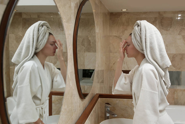 Kobieta robi anty wiek masaż twarzy przed lustrem po prysznicu, koncepcja pielęgnacji skóry piękna w domu - Zdjęcie, obraz