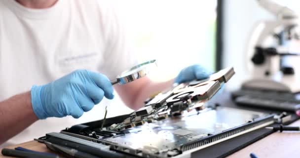 Closeup of person looking at computer board through magnifying glass. Repair of laptop and computer motherboards - Footage, Video