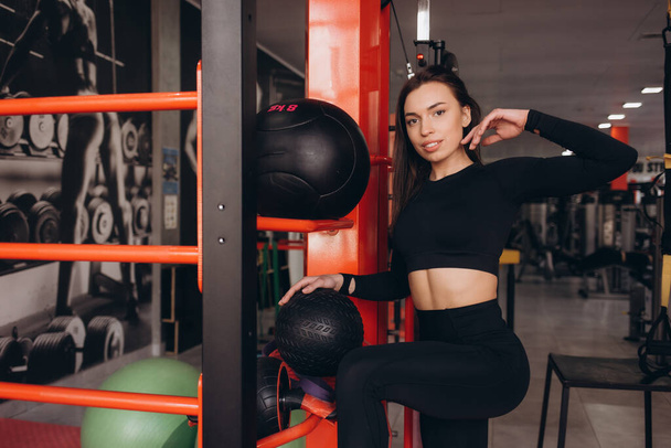 Спортивная девушка тренируется в спортзале. Женщина тренируется с мячом - Фото, изображение