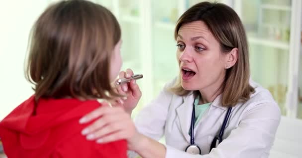 Lekarz ENT badanie gardła dziecka w klinice. Zapalenie migdałków u dzieci i wirusowe zapalenie migdałków - Materiał filmowy, wideo