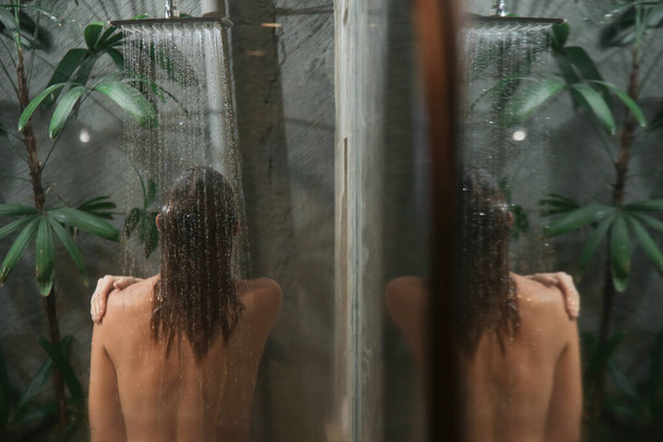 Young woman taking shower and washing her hair in shower cabine. - 写真・画像