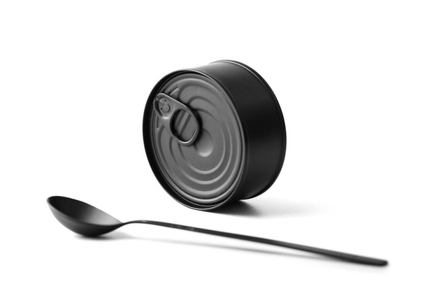 Black matte round closed tin can and black spoon on a white background isolated, tinned food, canned food, preserves. - Foto, Imagen