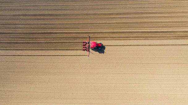 Obere Ansicht des Traktors als mechanische Sämaschine über Ackerfeld, Boden, neue Getreideernte, Mais, Mais. - Foto, Bild