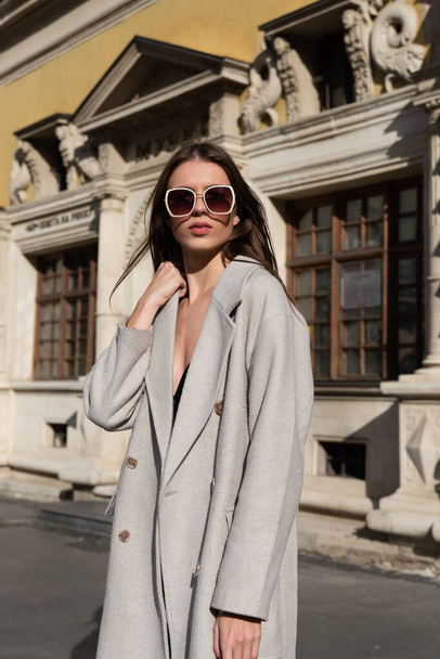 Street style, φθινόπωρο, άνοιξη έννοια μόδας: μοντέρνα γυναίκα φορώντας πολυτελές μπεζ παλτό, ένα top με ξυράφια και γυαλιά ηλίου - Φωτογραφία, εικόνα