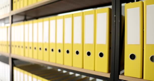 Szafki są wypełnione identycznymi żółtymi folderami w archiwum. Przechowywanie dokumentacji w organizacji przedsiębiorstw lub podatku - Materiał filmowy, wideo
