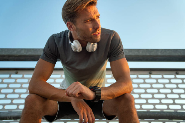 Young fit handsome man take a little break after training outdoor. Fitness sport people lifestyle concept - Foto, afbeelding