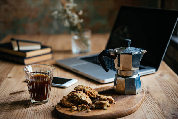 Coffee and some light snacks served during a break with laptop and books in the background. Working from home concept. - Photo, image