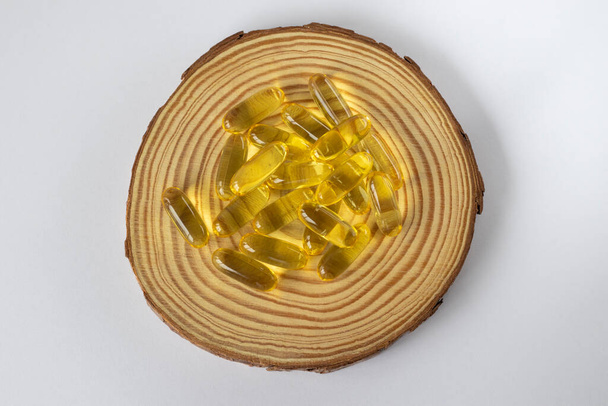 Omega 3 visolie capsules op hout en witte achtergrond - Foto, afbeelding
