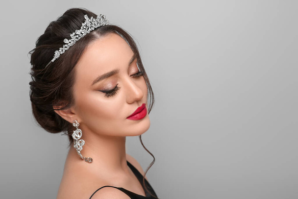 Beautiful young woman wearing luxurious tiara on light grey background, space for text - Foto, Bild